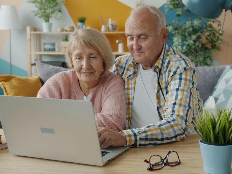 An older couple looking at a laptop together on the sofa